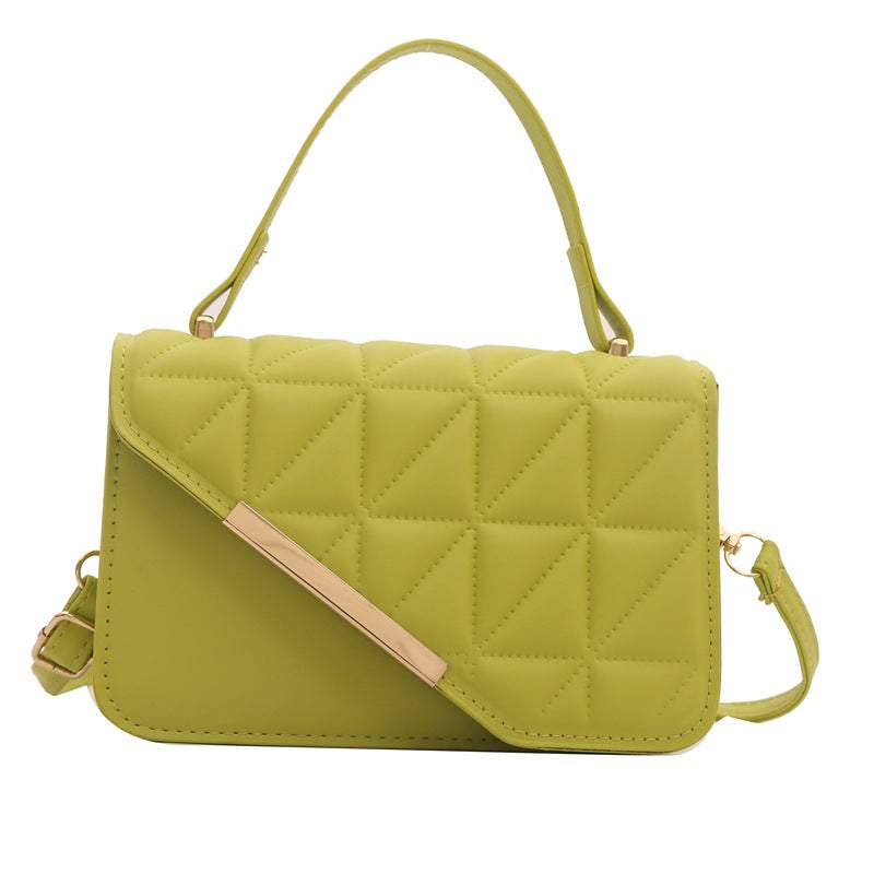 Green quilted handbag with a strap on a white background