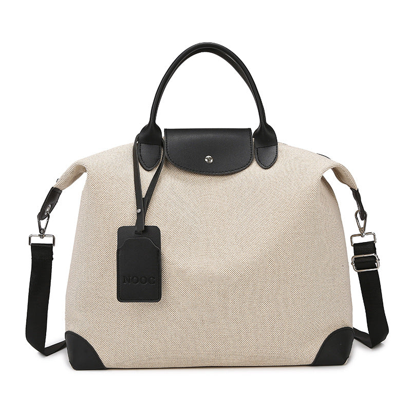 Beige handbag with black accents and a visible brand tag on a white background