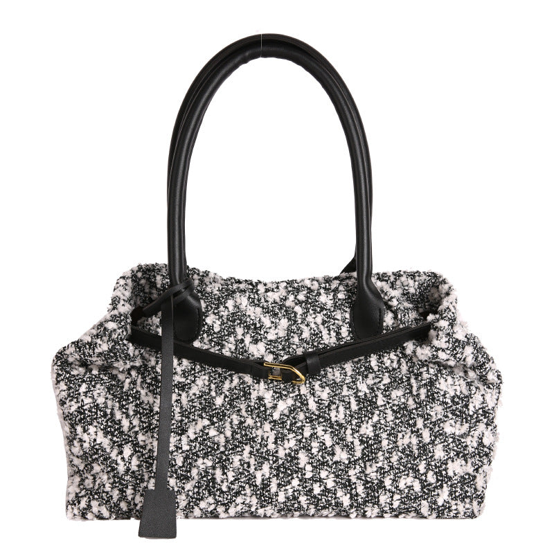 Black and white patterned handbag with a black handle on a white background
