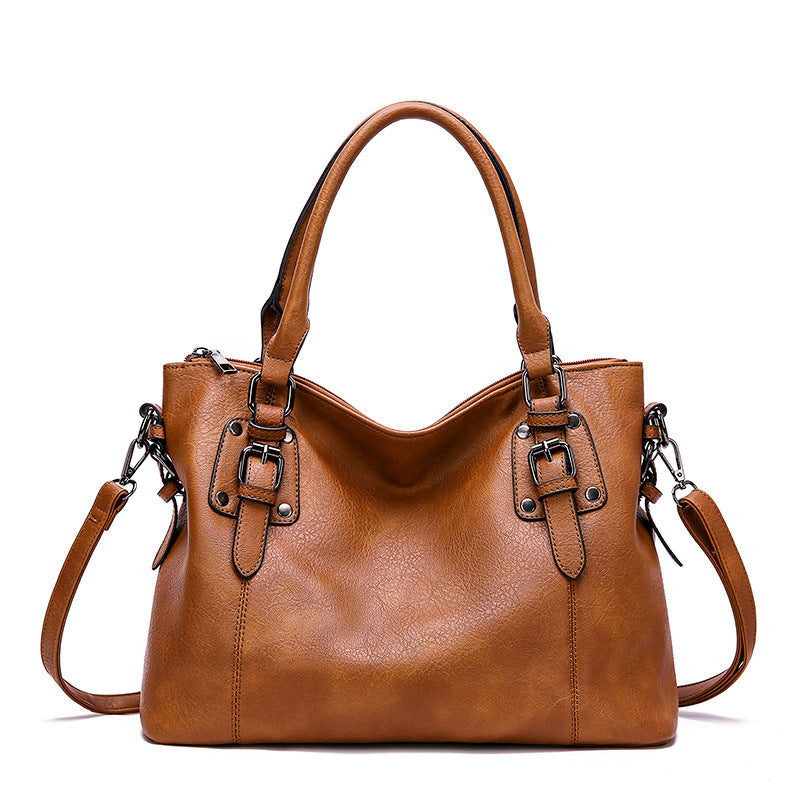 Brown leather handbag with metal buckles on a white background