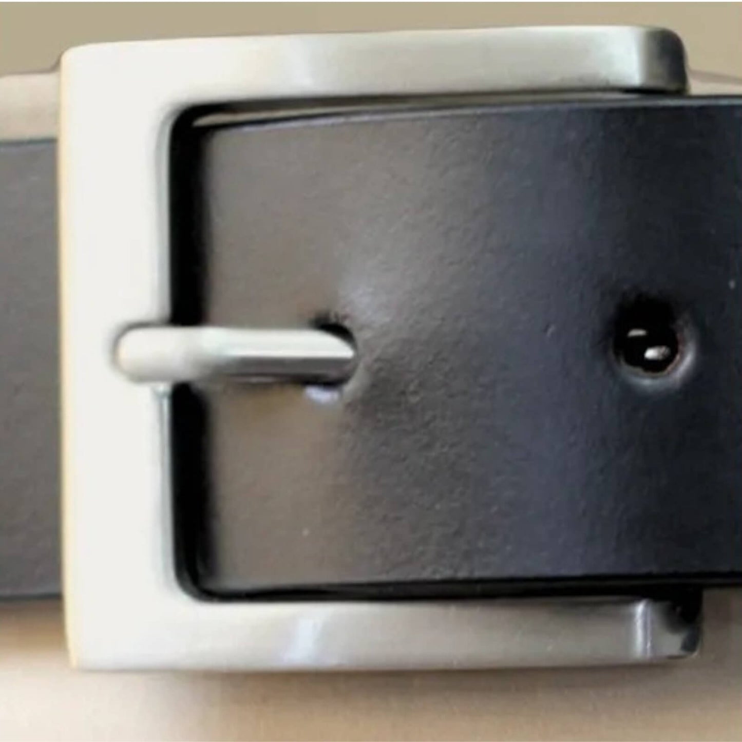 Close-up of a black belt with a silver buckle on a neutral background