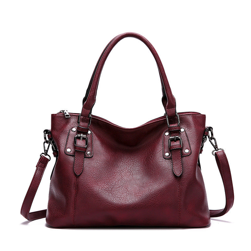 Maroon handbag with silver buckles on a white background